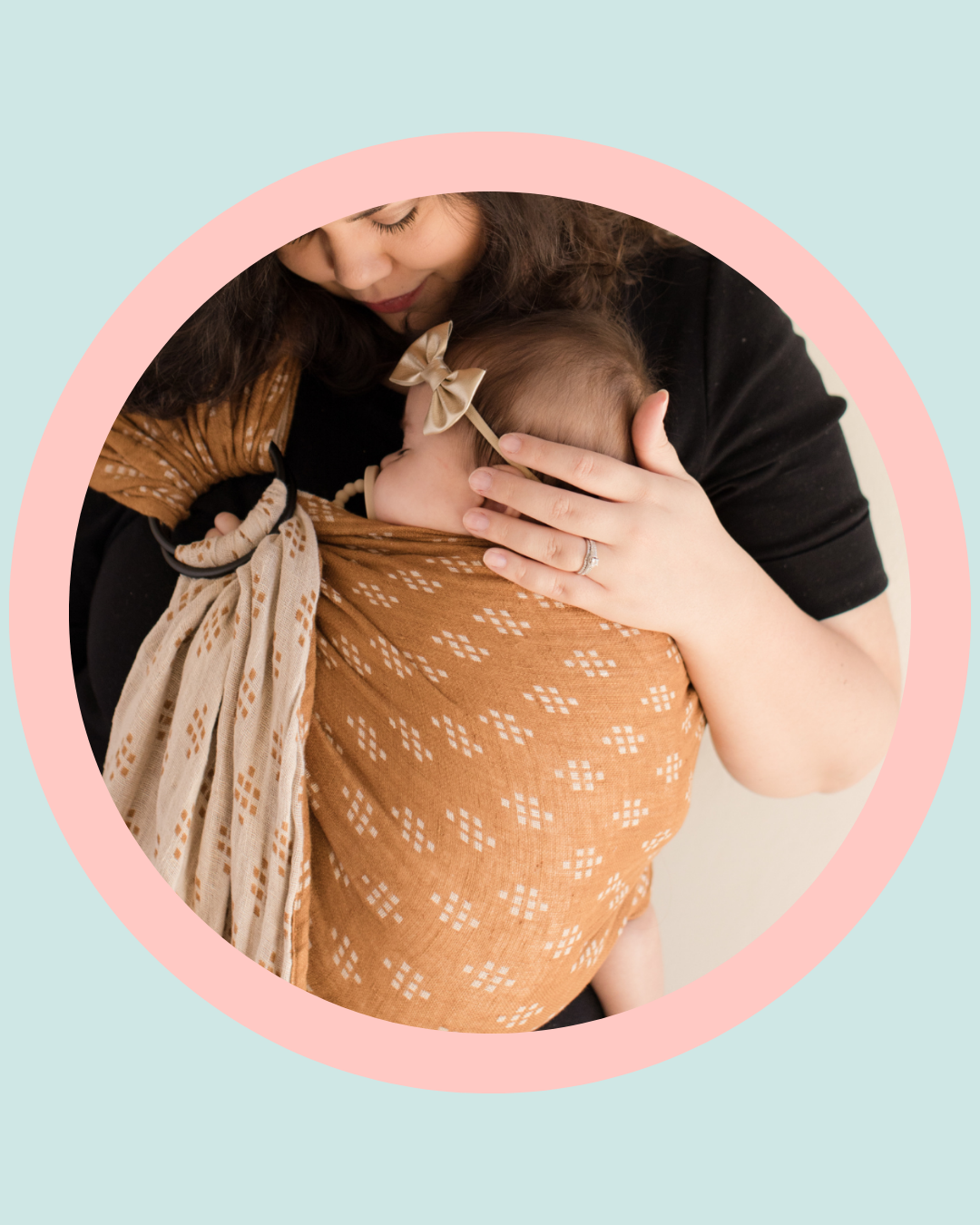 Mother holding baby in a brown sling, representing bonding, feeding support and oral ties education for parents of babies.