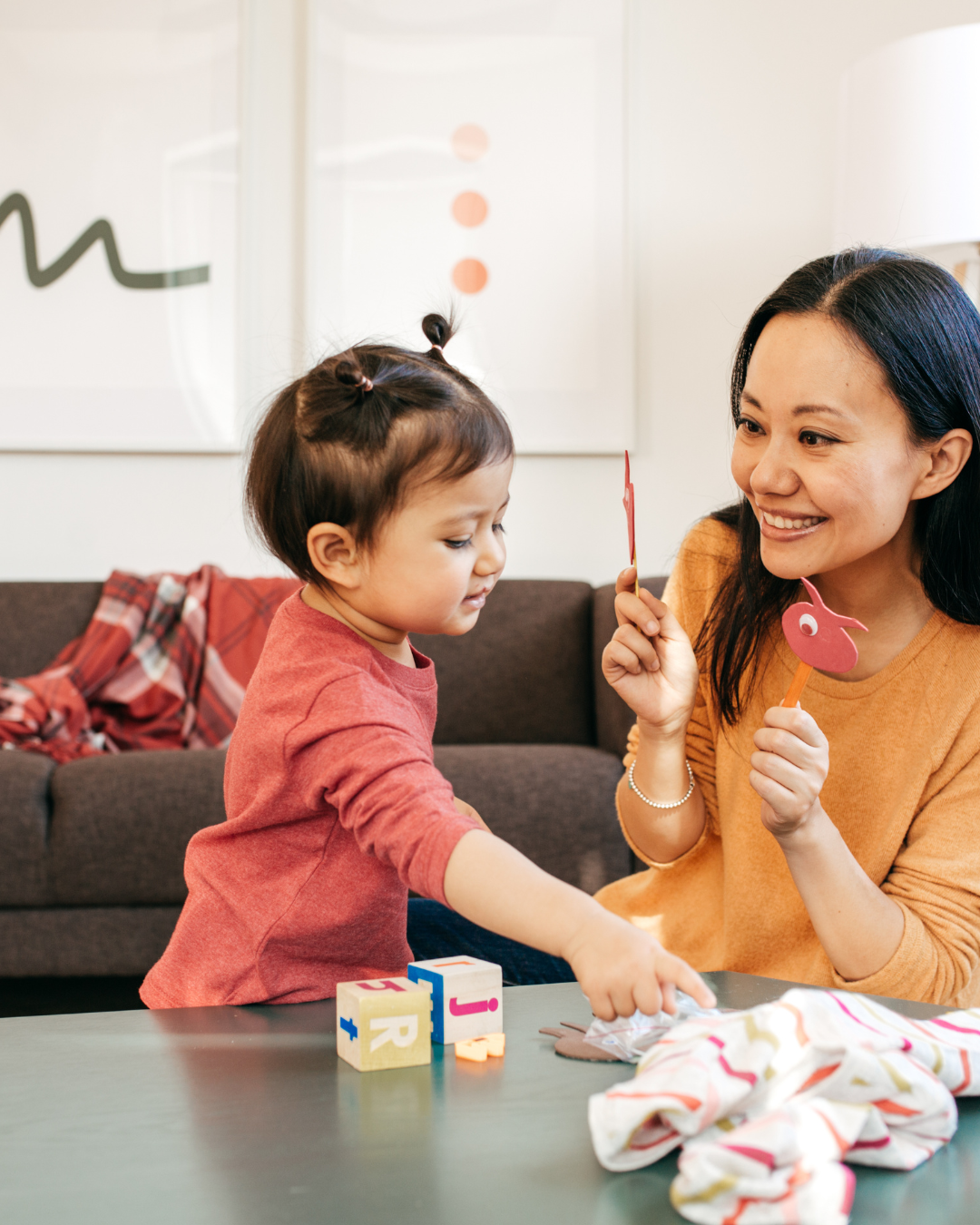 Parent and toddler playing together at home with toys and puppets, illustrating positive connection and early learning routines related to oral and developmental health.
