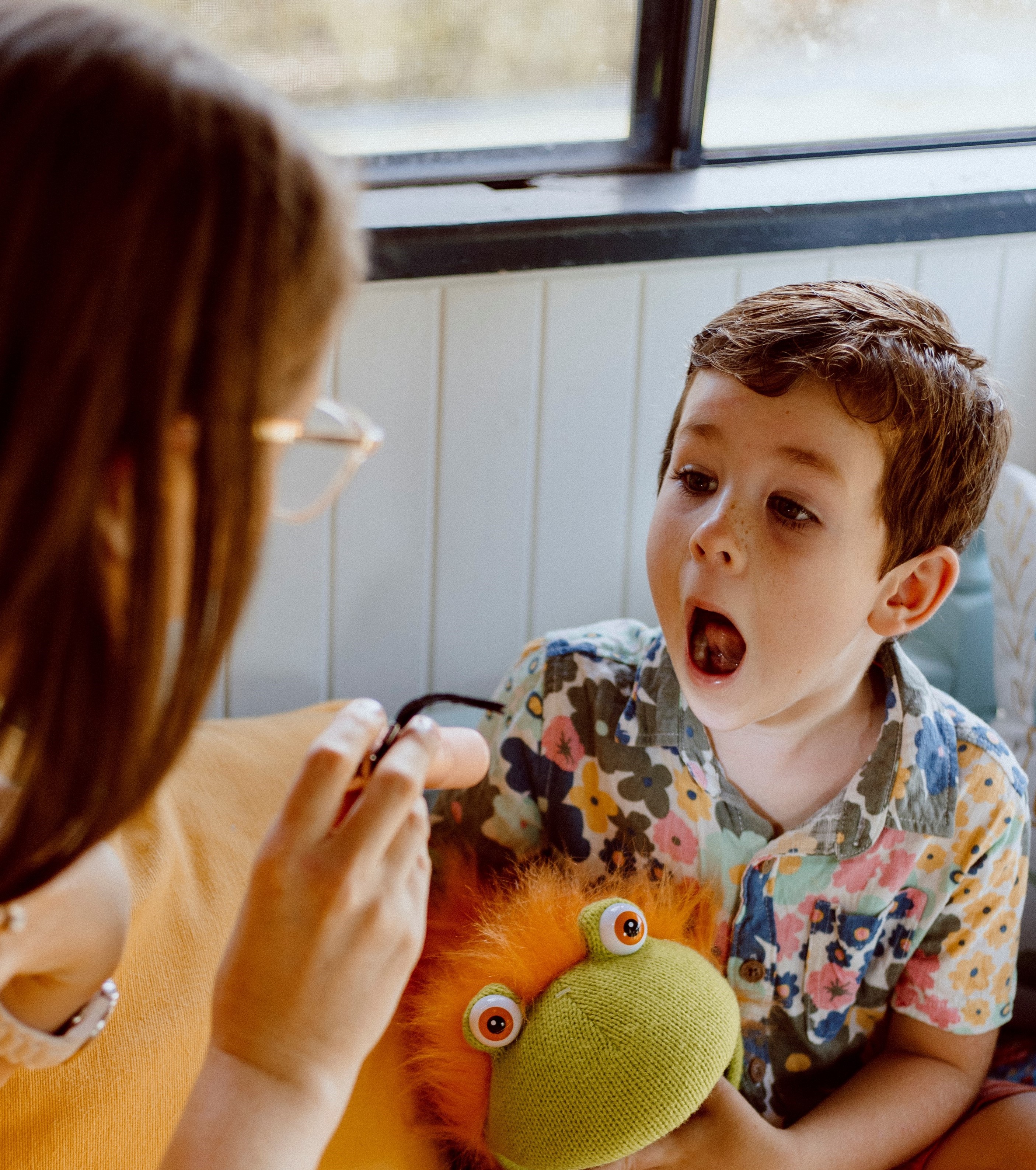 A children’s oral health therapist engaging a young child with a puppet during an online oral health consultation.