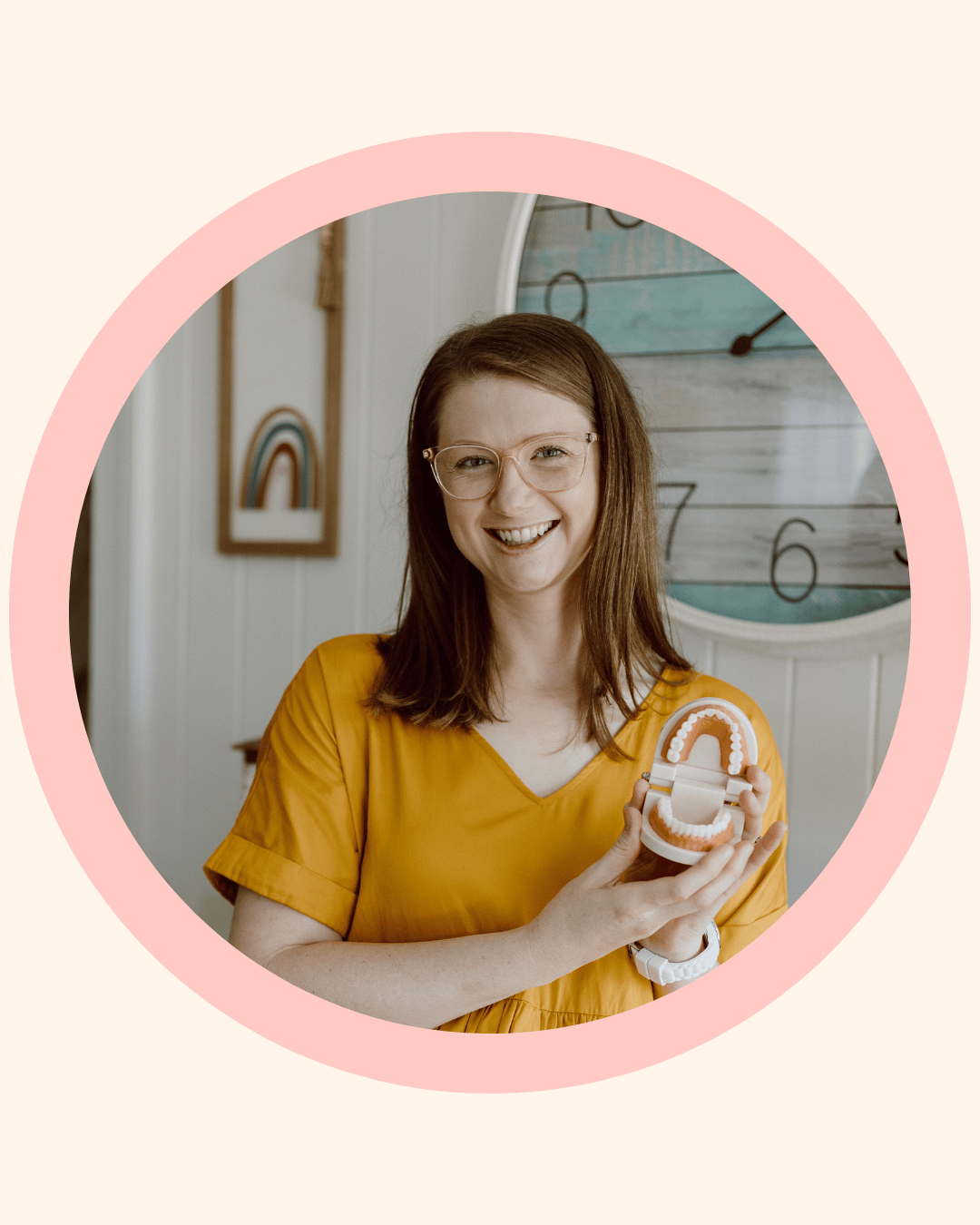 Holistic dental practitioner smiling and holding a dental model to demonstrate children’s oral health and development education.