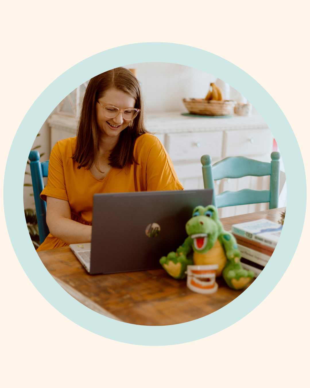 The Face Place founder, a holistic dental practitioner, smiling while working on her laptop in a bright, welcoming home clinic space, supporting parents with children’s oral health and early intervention care.
