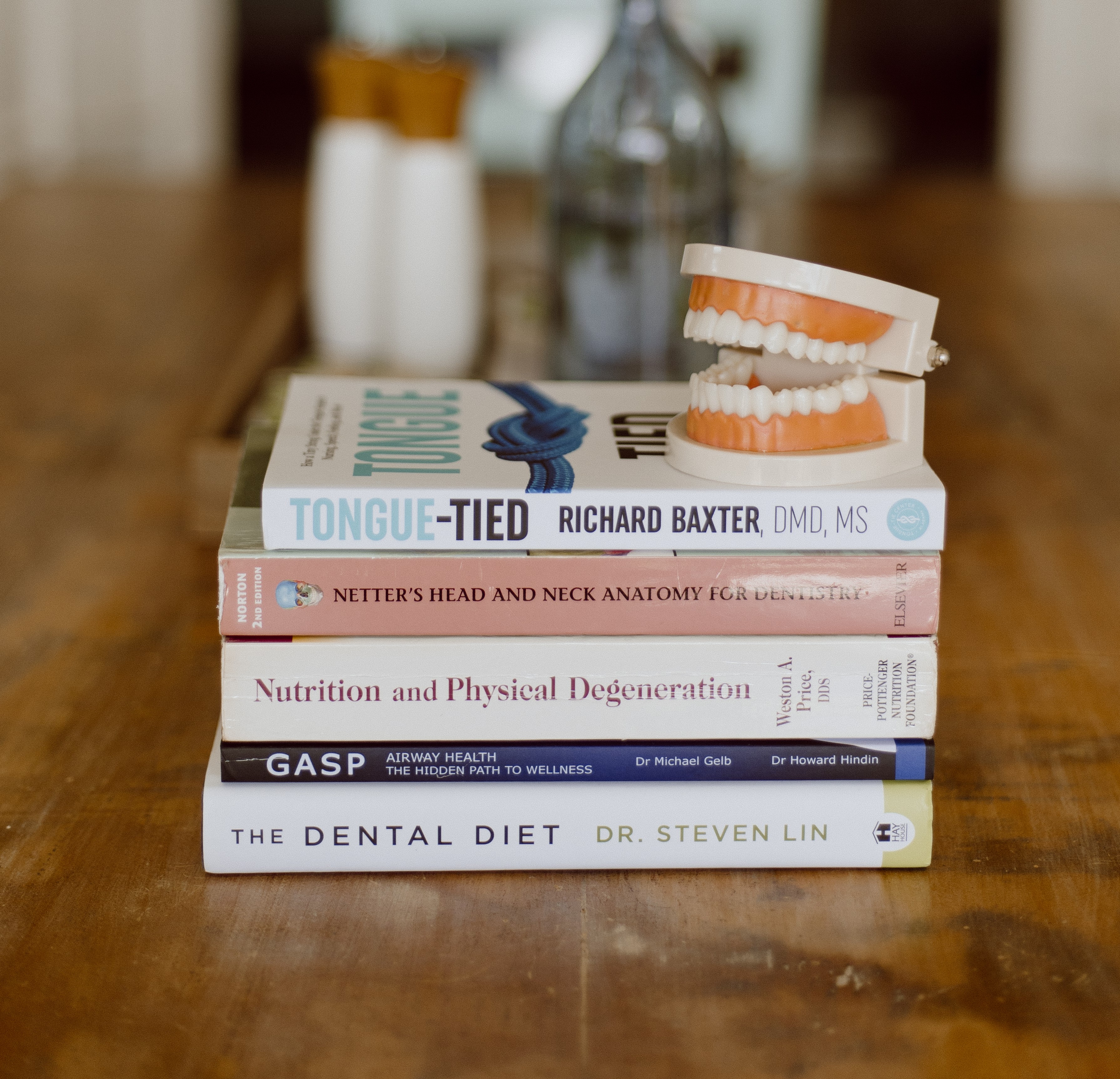 Stack of dental and airway health books with a dental model on top, representing evidence-based learning and free oral health guides for parents.